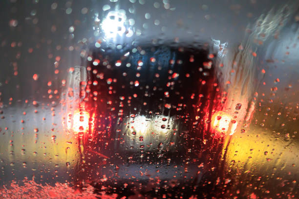 Wet snow on the windshield of a car on a night road in a traffic jam