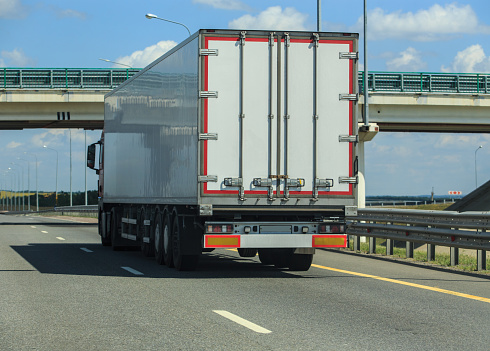 Truck moves along the highway under a bridge near a traffic intersection