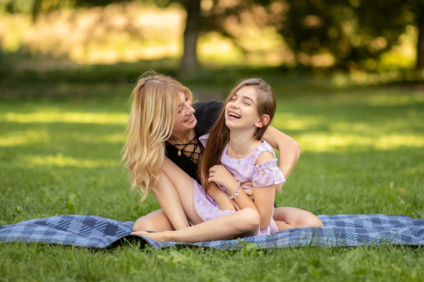 istock Mother and daughter laughing while sitting on a picnic blanket 1950930380