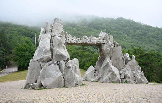 Stone arch at Mashuk Mount in Pyatigorsk, Stavropol Krai, Russia. Landscape with tourist attraction in Russian Caucasus Mountains. Theme of nature, travel in Pyatigorsk, gate, hike, forest and mist.