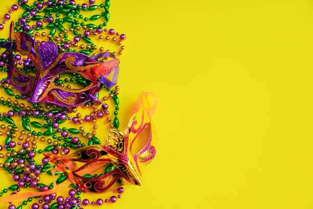 istock Two multi-colored carnival masks and beads on yellow background. Mardi Gras concept. Fat Tuesday symbol. 1950970027