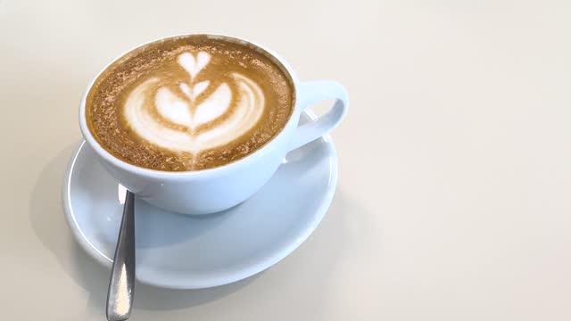 Cappuccino with heart-shaped foam on a brown background.