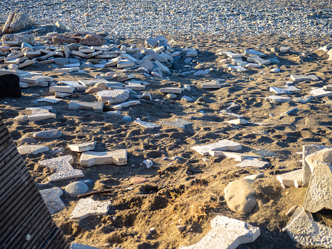 Paving slabs are scattered on the sand. Embankment after the storm. Construction garbage.
