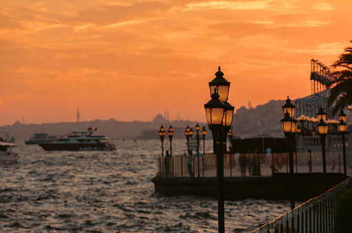 City lamps on the coast line and silhouetted Istanbul sunset view on the Bosphorus from Ortaköy in Turkiye