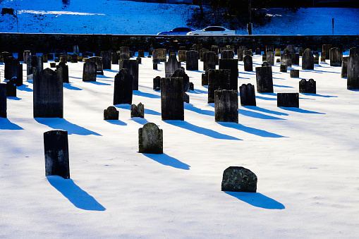 Snow-covered Wooster Street Cemetery in Danbury, Connecticut, one of the oldest cemeteries in United States with old tombstones on a bright sunny winter day