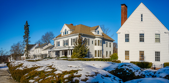 Historic district street winter landscape with landmark colonial houses and gardens covered with snow in New England, United States