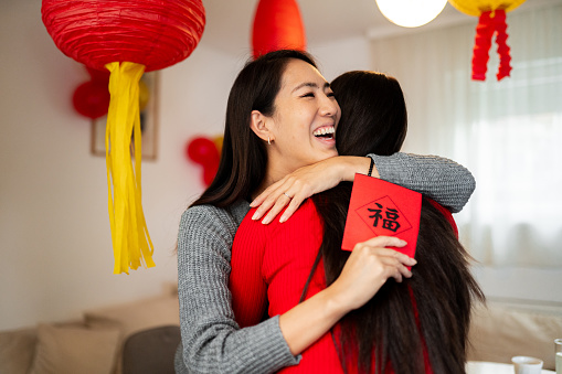 Two young friends laughing while exchanging their Chinese New Year gifts