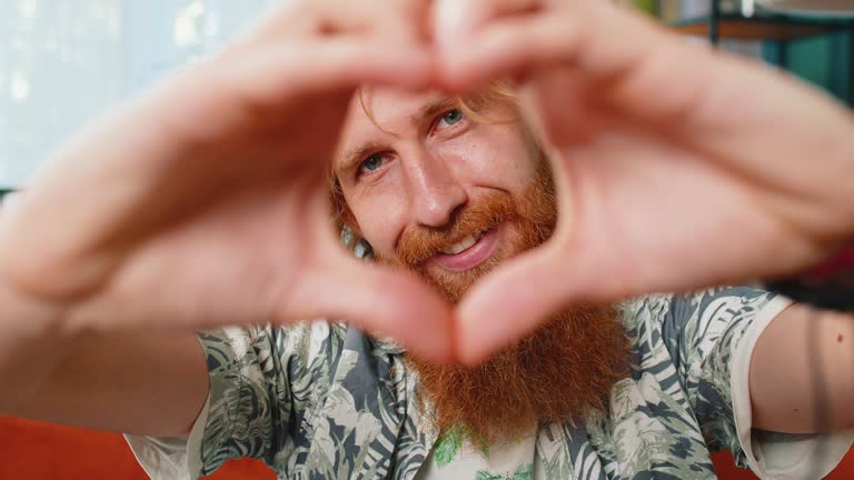 Happy Caucasian man guy makes symbol of love showing heart sign to camera express romantic feelings