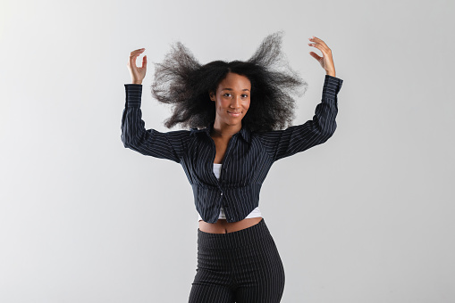 Young adult businesswoman with a cheerful smile posing confidently, corporate fashion and natural hair beauty.