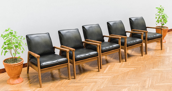 Five wooden chairs with black cushions next to pots on a white wall and brown floor stage, spaces and interiors, 3D illustration, horizontal image