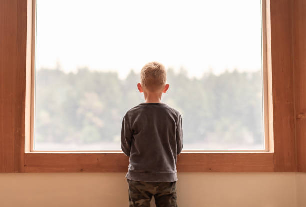 cute toddler baby watching the cityscape from the rooftop patio with glass balustrade