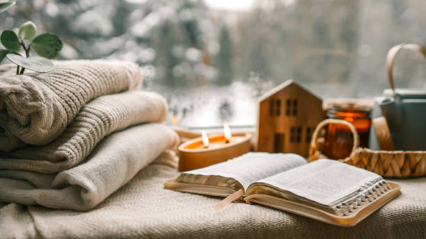 istock Cozy winter photo, stack of sweaters, open Bible, tea and candle 1951187401