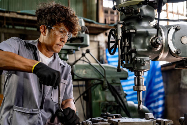 istock Engineer worker in production plant drilling at machine. Professional worker near drilling machine on factory. man inspecting and repairing machine for operation in workshop. 1951209029