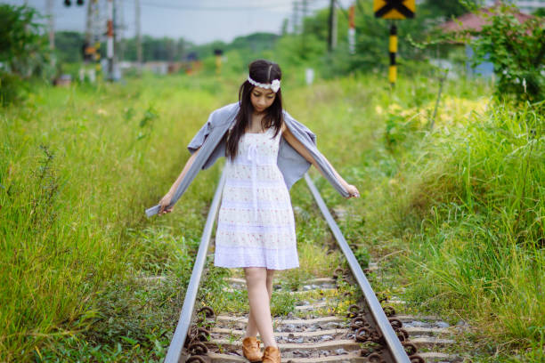 Woman on railroad station platform waiting for a local train to arrive at European countryside