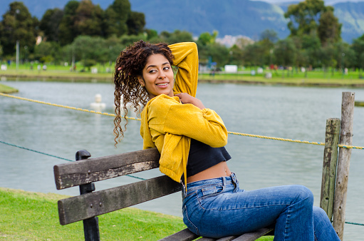 Beautiful young black woman with curly hair dressing casual clothes on public park