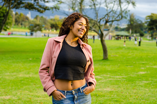 Beautiful young black woman with curly hair dressing casual clothes on public park