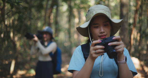 istock Two Young asian backpacker women walking in trail with digital camera in forest 1951304909