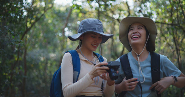 istock Two Young asian backpacker women walking in trail with digital camera in forest 1951305936