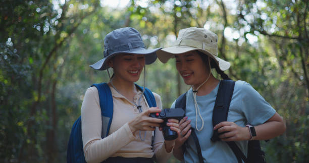 istock Two Young asian backpacker women walking in trail with digital camera in forest 1951305937