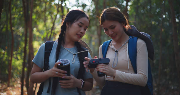 istock Two Young asian backpacker women walking in trail with digital camera in forest 1951308543