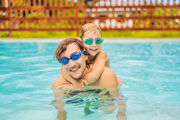 Dad and son in swimming Goggles have fun in the pool