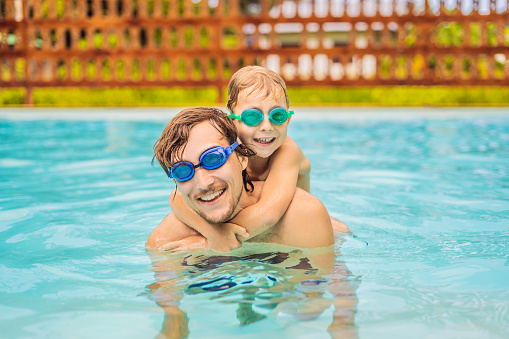 Dad and son in swimming Goggles have fun in the pool.