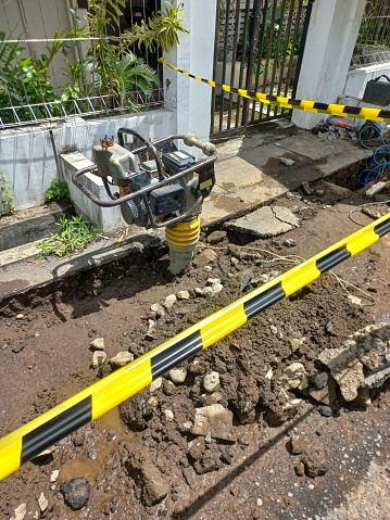 Worker Compacting Soil with Vibratory Rammer Tamper on a Home Construction Site. Worker uses compactor to firm soil at worksite.