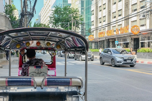 Bangkok, Thailand - Nov 01, 2023: Tuk tuk driver waiting for customers in front of Patpong Night Market on a quiet morning in Silom, Bang Rak