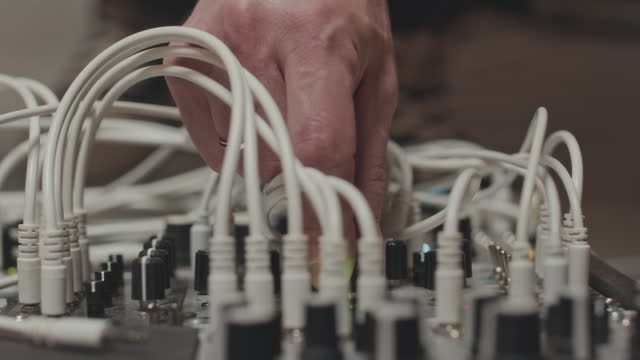 Hand of Musician Plugging Audio Cables into Modular Synthesizer