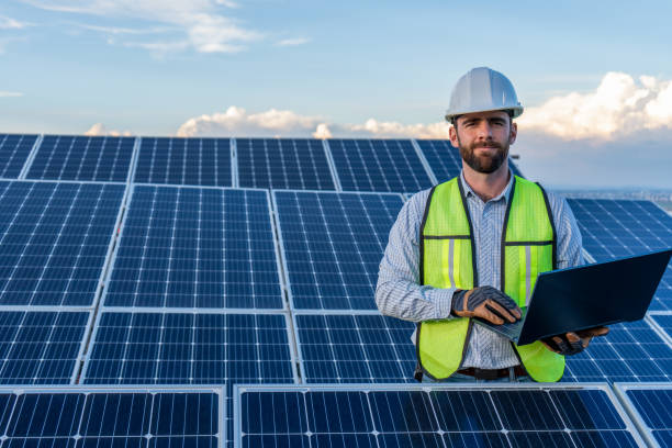 istock portrait of an engineer smiling with confidence using a laptop in front of a solar panel power station, handsome male technician electrician looking at camera holding a computer 1951513694