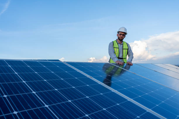 istock engineer looking at the camera smiling after installing solar panels, concept of renewable energy power, technician working on a roof with blue sky background; horizontal photography with copy space 1951513965