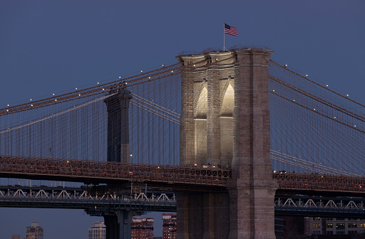 Brooklyn Bridge illuminated with lights shining on towers at dusk