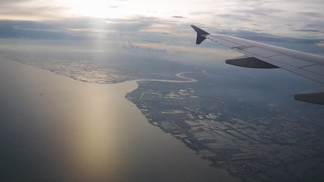 Footage of aerial view from airplane window, landing aircraft, plane descending over clear sky seeing landscape and river below, travel by air