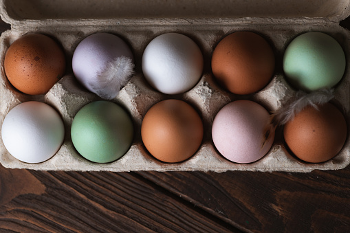 Box of white eggs with one brown egg, square egg carton on gray background. Easter eggs. Shot from directly above.