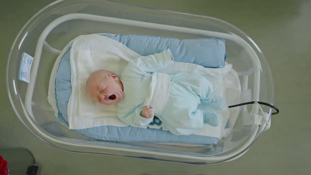 HA Tiny Yawns: Newborn Baby Boy Finds Peace in Hospital Crib at Maternity Ward
