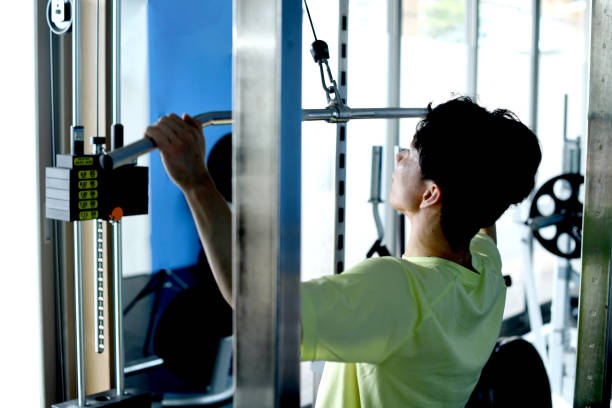istock Rear view of a young Asian man doing lat pulldown machine training at the gym 1951624057