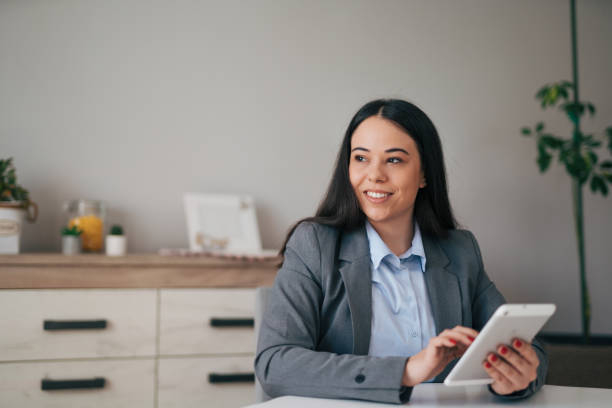 istock Smiling young businesswoman relaxing at home and using tablet 1951661189