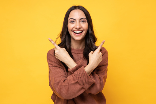 Photo of young women in winter wear standing on yellow background