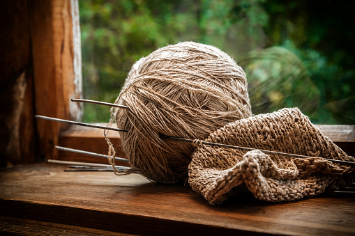 Brown balls of knitting thread with knitting needles on an old rustic window. The beginning of the knitting process. Retro style