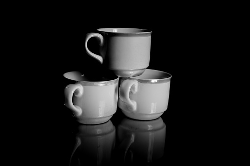 reflection of ceramic cups stacked against a dark background with dim light