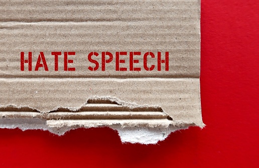 Torn brown cardboard paper with red text HATE SPEECH on red background, concept of expression which speakers intend to humiliate or promote hatred, violence and discrimination against group or class of persons