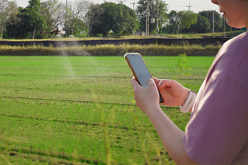 Woman using a mobile phone in a farm, surrounded by farm, control Agriculture Petrol Drone Sprayer .