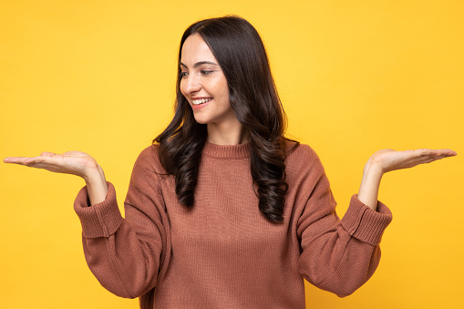 Photo of young women in winter wear standing on yellow background