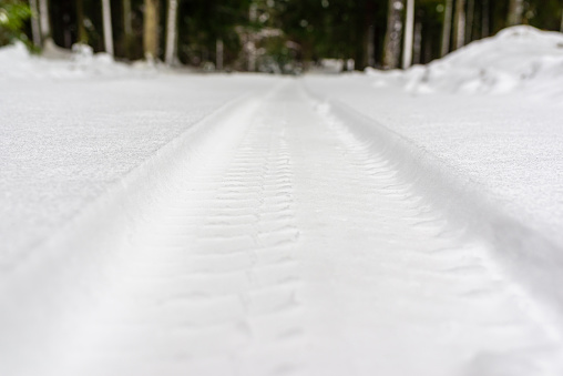 Snowy tire tracks on the winter rural road near forest.close-up,copy space.