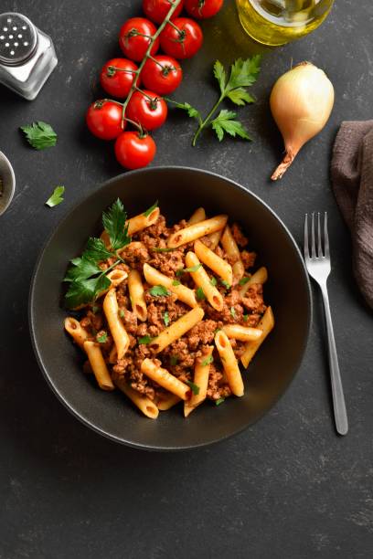 istock Penne pasta with minced meat, tomato sauce and greens 1951705761