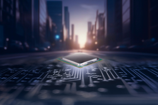 An innovative integrated circuit is prominently positioned in the center of an urban street, with the city skyline silhouetted against a twilight sky in the background, suggesting a blend of technology and infrastructure.