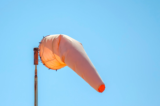 An orange windsock at a rural airport on a clear and calm evening.