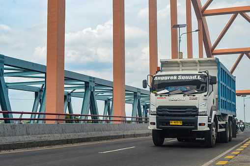 An Isuzu Giga dump truck passes over a concrete arch bridge, Indonesia, 16 January 2024.