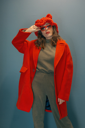 Brunette woman in all red poses while standing against a gray wall