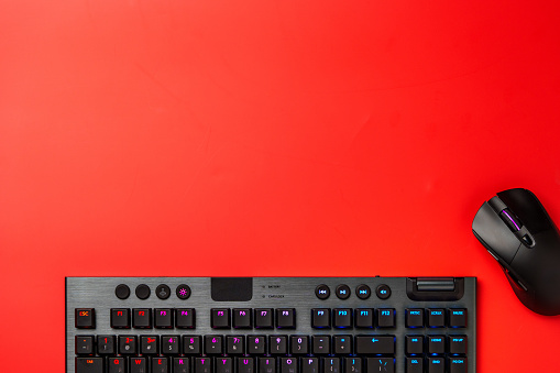 Computer keyboard and mouse on red background top view photo